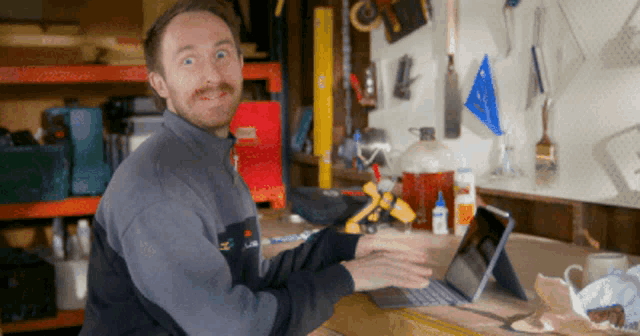 a man sitting at a desk with a laptop and a sweatshirt that says ' ll bean ' on it