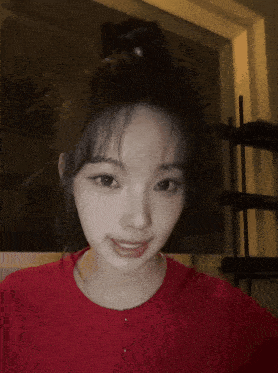 a girl in a red shirt making a heart with her hands