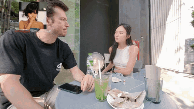 a man and a woman sit at a table with a green drink in front of them and a watermark that says " just uploaded "