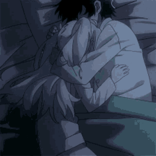 a man and a woman are hugging each other while laying in bed .