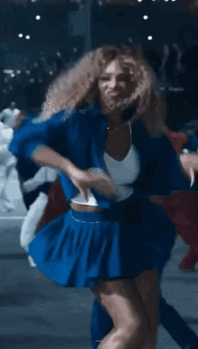 a woman in a blue skirt and white top is dancing in a crowd .