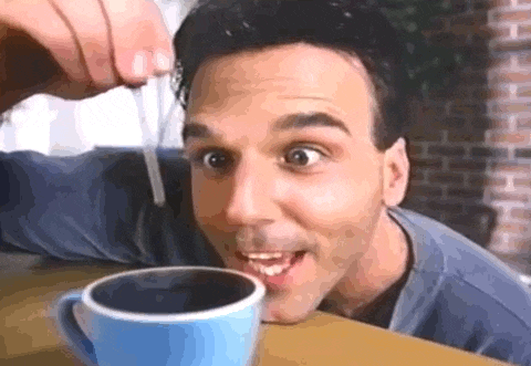 a man is sitting at a table with a cup of coffee and a straw in his mouth .