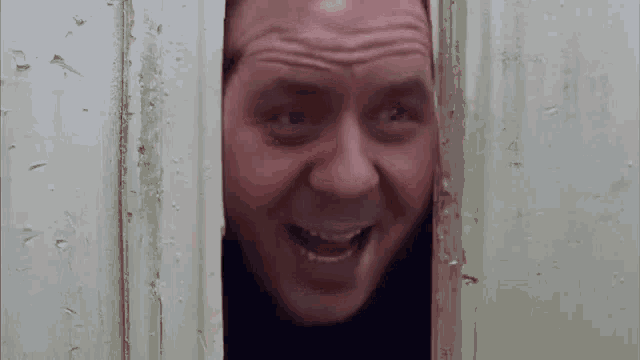 a man is peeking out of a doorway with his mouth open .