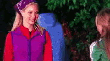 a girl in a purple vest is talking to another girl in a green shirt