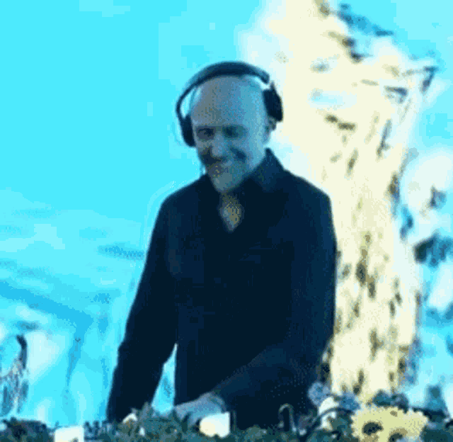 a bald man wearing headphones is playing music on a table