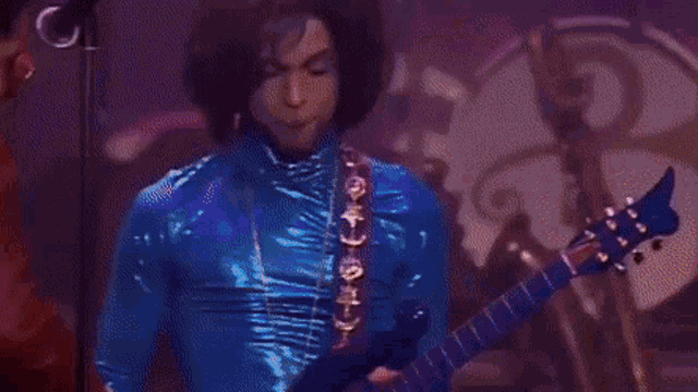 a man in a blue suit is playing a guitar next to another man