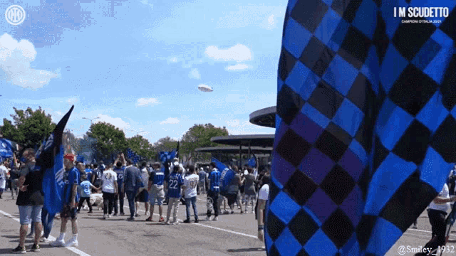a group of people are gathered in a parking lot with a sign that says i 'm scudetto on it