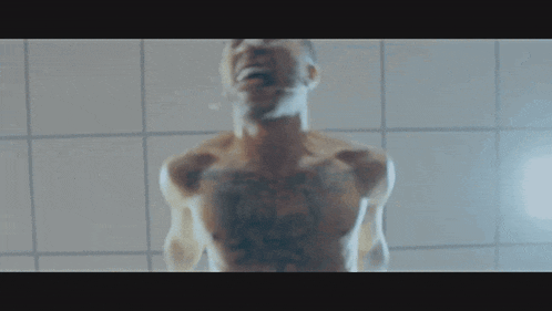 a man without a shirt is standing in front of a white tiled wall