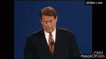 a man in a suit and tie is speaking into a microphone on october 3rd 2000