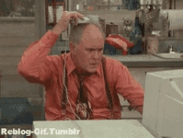 a man in a red shirt and tie is sitting at a desk