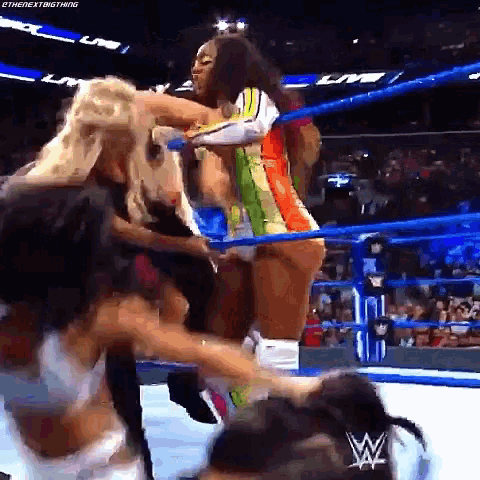 a group of women are wrestling in a wrestling ring with a crowd watching .