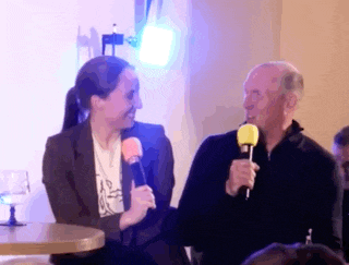 a man and a woman are sitting at a table with microphones in their hands