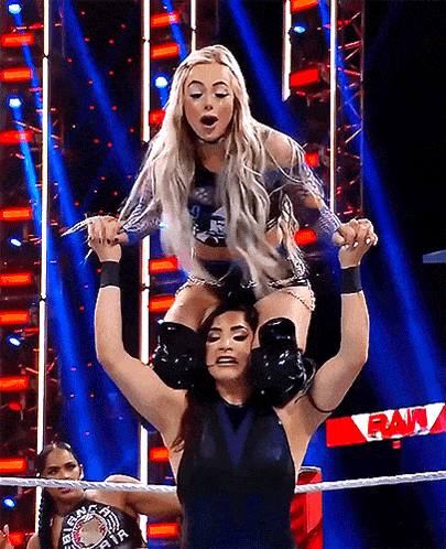 a female wrestler is carrying another wrestler on her shoulders in a ring that says raw on it