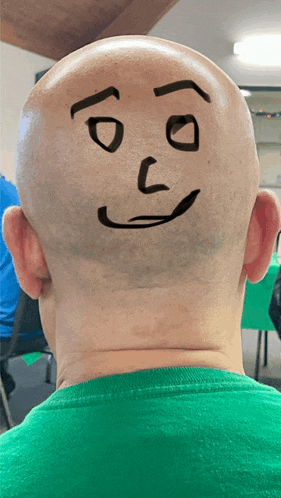 a bald man has a face drawn on his head