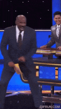 a man in a suit and tie is dancing on a stage with the website gifrun.com in the lower right corner
