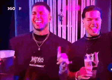 two men are standing next to each other in a room with purple lights .