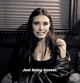 a woman is sitting on a couch wearing a leather jacket and a black top .