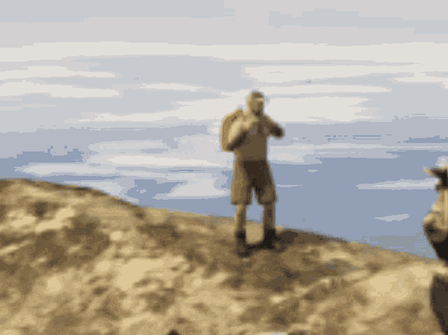 a man with a backpack is standing on top of a hill overlooking the ocean