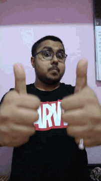 a man wearing a black shirt that says ' army ' on it gives a thumbs up