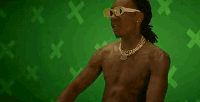 a shirtless man wearing sunglasses and a necklace is standing in front of a green background .