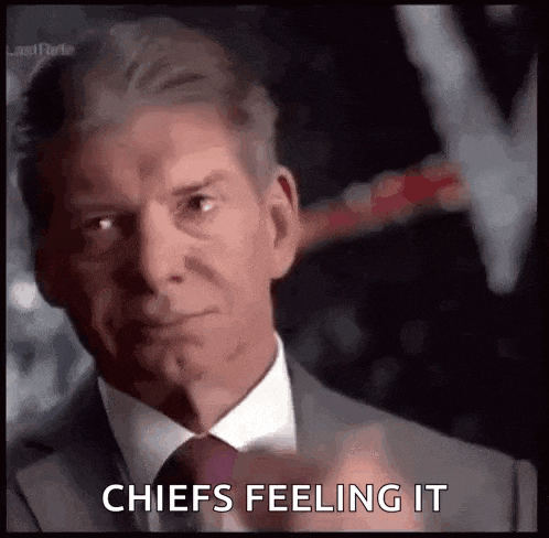 a man in a suit and tie is pointing at the camera and saying chiefs feeling it .