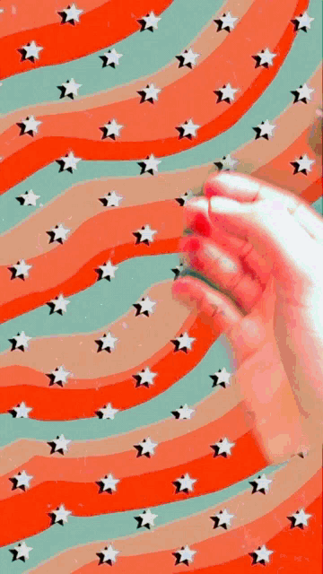 a person 's hand is against a colorful background with stars and waves