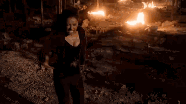 a woman is standing in front of a fire in the dark .