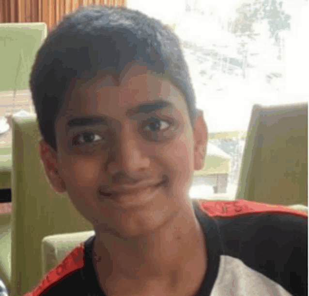 a young boy is sitting in a chair and smiling for the camera .