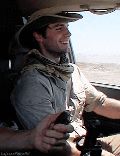 a man wearing a hat and scarf is holding another man 's hand in a car