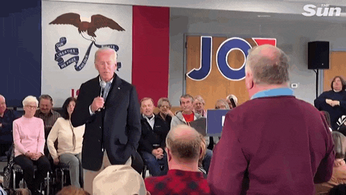 joe biden is giving a speech in front of a crowd