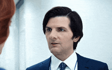 a man in a suit and tie talks to a woman