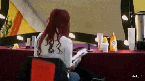 a woman with red hair is sitting at a table reading a magazine ..