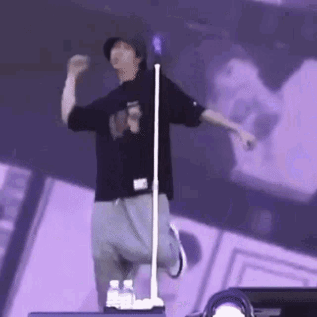a man is standing on a stage in front of a microphone and dancing .