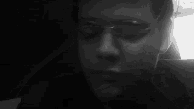 it is a black and white photo of a person smoking a cigarette .
