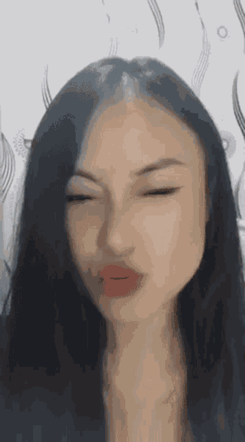 a woman with long black hair is making a funny face .