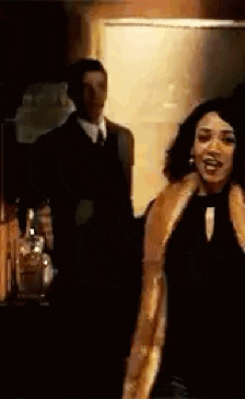 a woman in a fur coat is standing in front of a man in a suit .