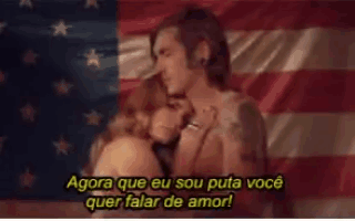 a man and a woman are kissing in front of an american flag with the words agora que eu sou puta você quer falar de amor