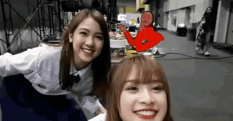 two girls are posing for a picture and one has a red arrow pointing at her head