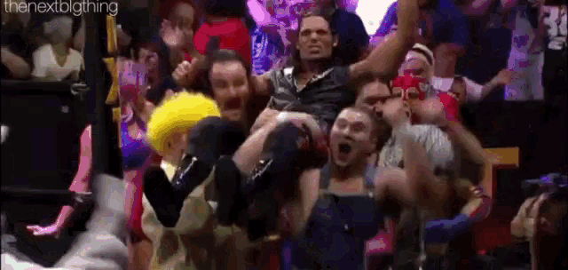 a group of people are holding a wrestler in their arms in a crowd .