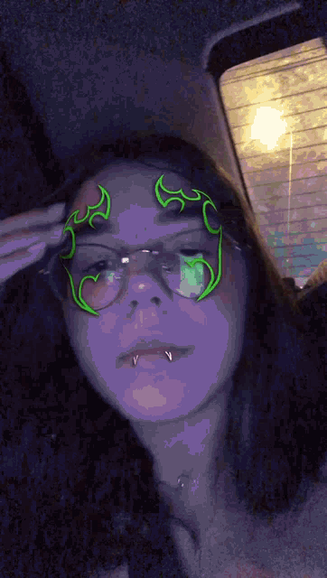 a girl wearing glasses has a green flame on her forehead
