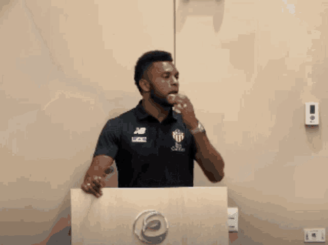 a man stands behind a podium wearing a shirt that says ' new balance ' on it