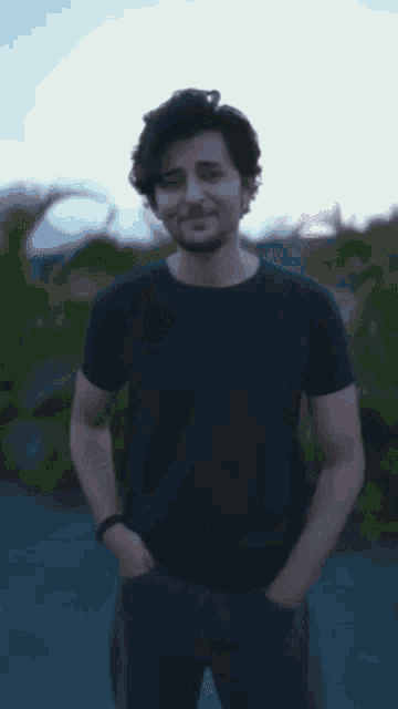 a young man wearing a black t-shirt and jeans smiles for the camera