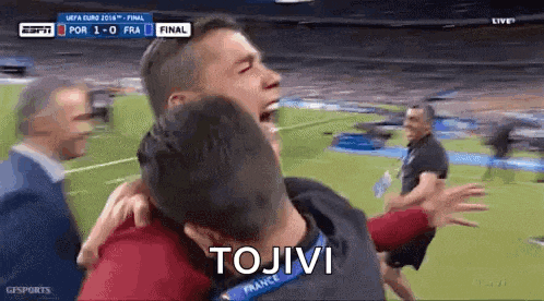 a man is hugging another man on a soccer field with the word tojivi on the bottom