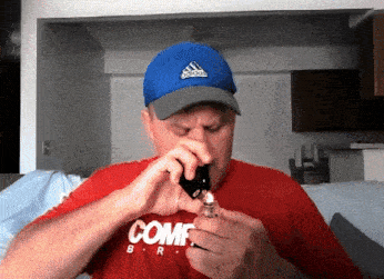a man wearing a blue adidas hat and a red shirt that says comf
