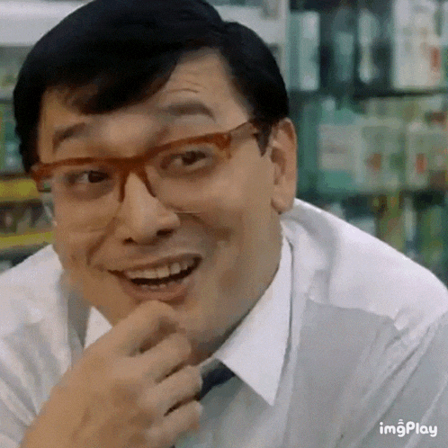 a man wearing glasses and a white shirt is smiling and laughing in a store .