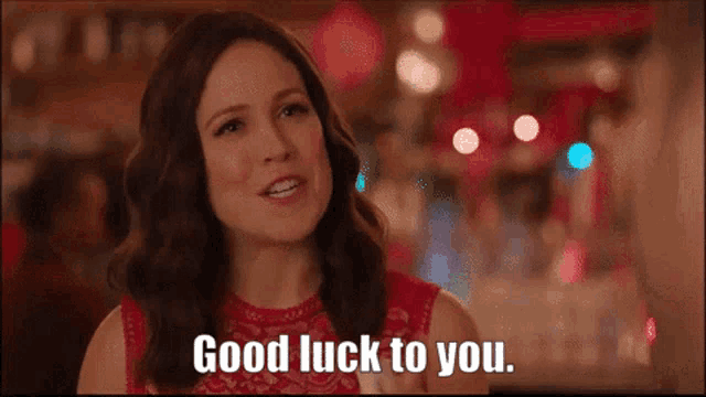a woman is smiling and saying good luck to you