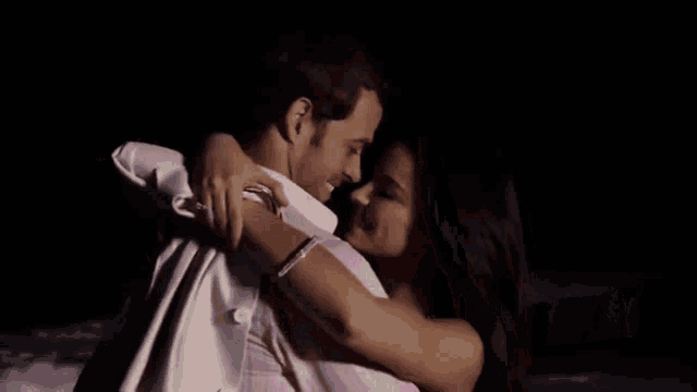 a man in a pink shirt is hugging a woman in a silver bracelet