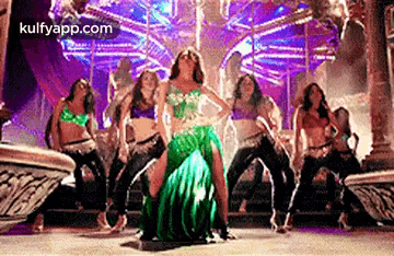 a group of women are dancing together on a stage in front of a crowd .
