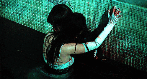 a woman in a bathtub with blood on her hands is hugging another woman