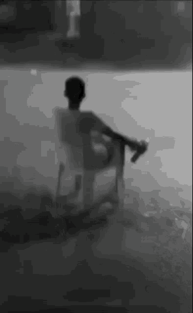 a black and white photo of a man sitting on a rocking chair